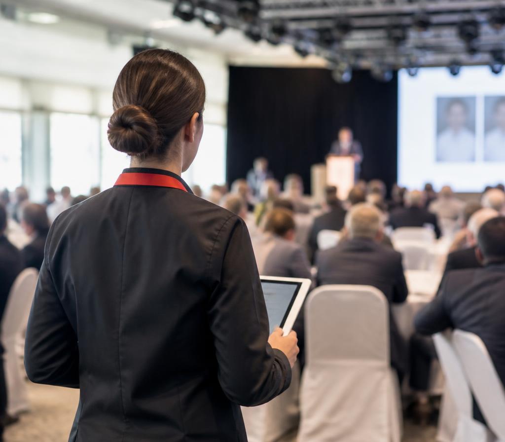 Onsite coordinator with a tablet overseeing a conference plenary session